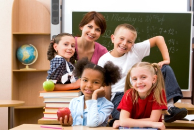 Elementary School Teacher at Desk with Students